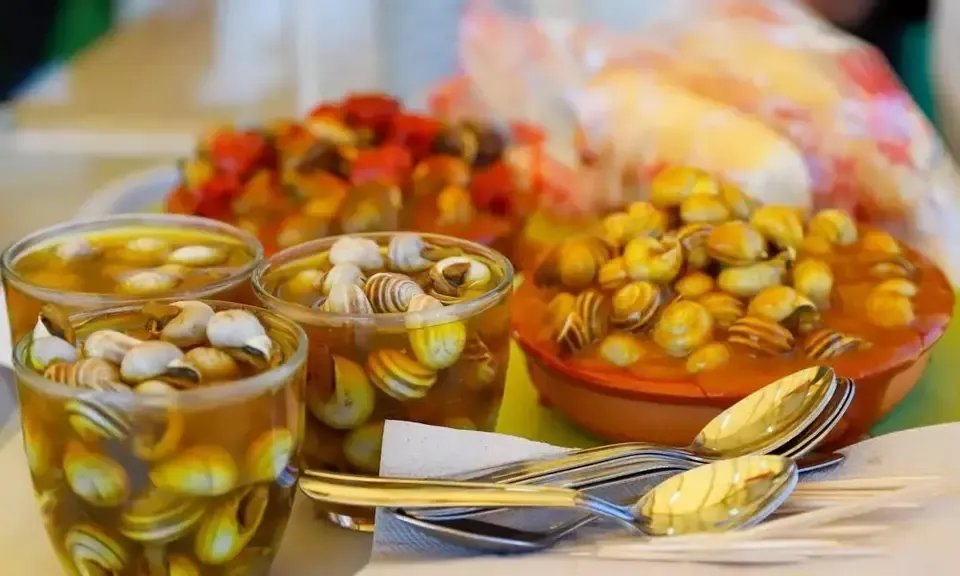 Verre de caracoles avec bouillon aromatique fumant et épingle traditionnelle sur un comptoir de bar