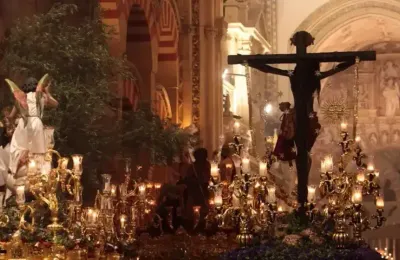 Procession nocturne de pénitents encapuchonnés devant la Mezquita illuminée lors de la Semaine Sainte de Cordoue
