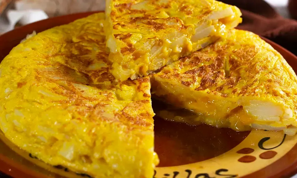 Tranche épaisse de tortilla de patatas dorée et crémeuse servie sur une assiette