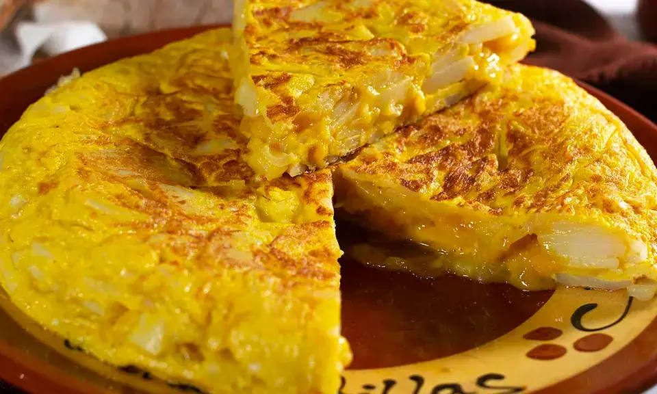 Tranche épaisse de tortilla de patatas dorée et crémeuse servie sur une assiette
