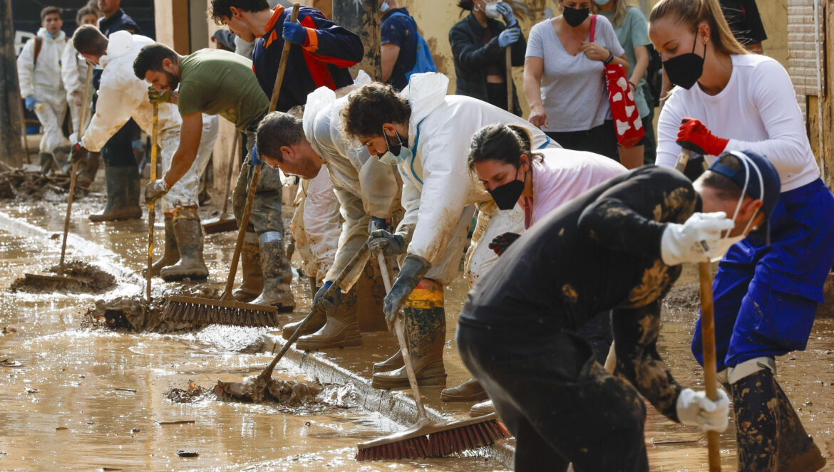 Un grupo de voluntarios limpia una calle en una localidad valenciana afectada por la DANA / EFE