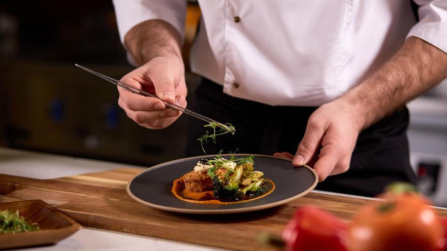 Chef elaborando plato con verduras frescas / Shutterstock