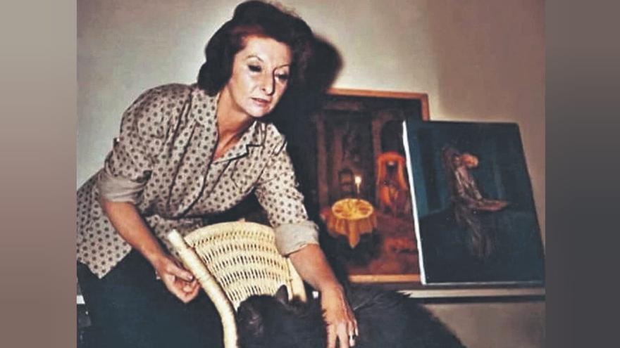 Remedios Varo, junto a algunos cuadros recién pintados, acaricia a su gato. / CÓRDOBA