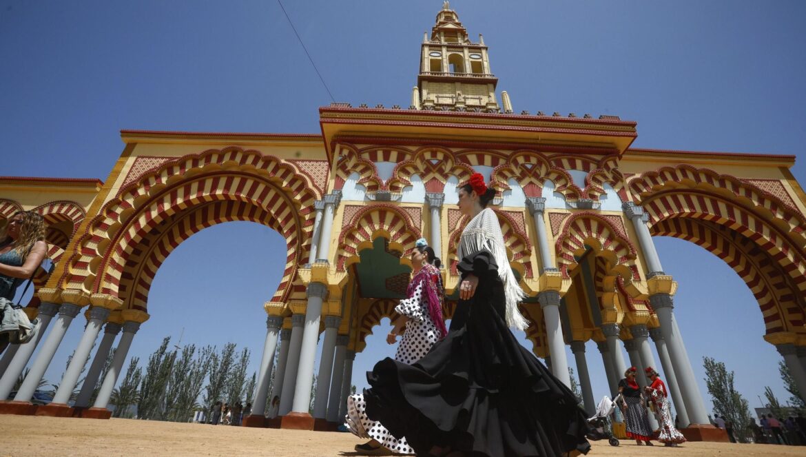 Mujeres con traje de flamenca, junto a la portada de la Feria de Córdoba. / Salas / Efe