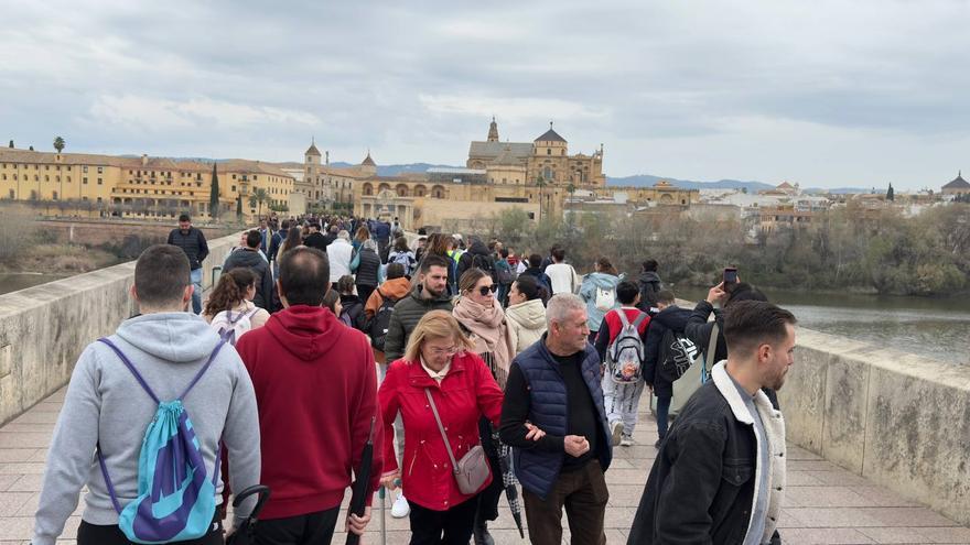 Turistas, algunos con el paraguas en la mano, pasean por el Puente Romano de Córdoba el 28 de febrero. / Ramón Azañón