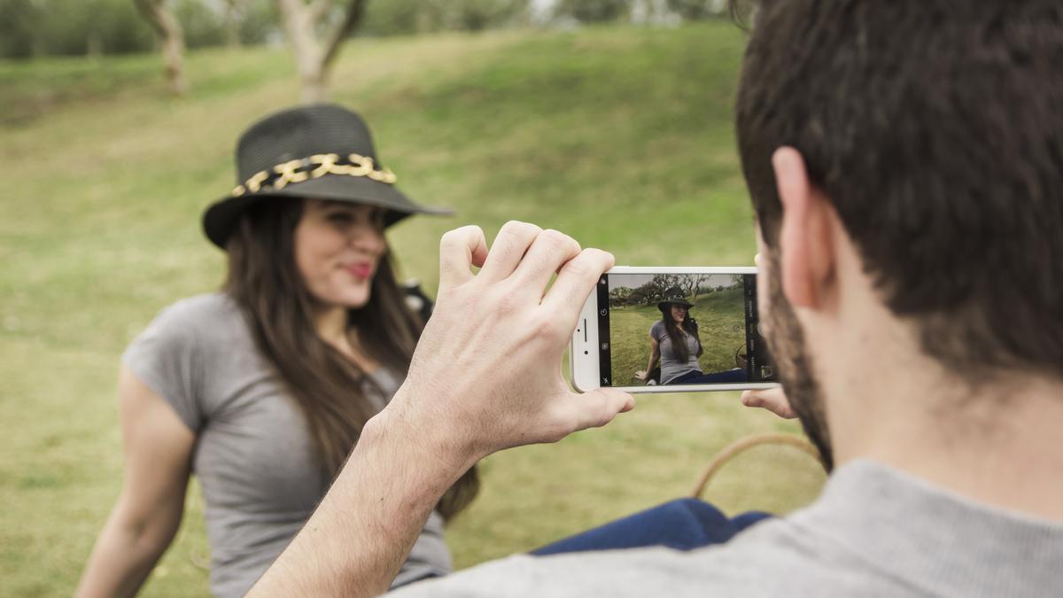 Un fotógrafo toma una imagen de una mujer en la naturaleza | FREEPIK