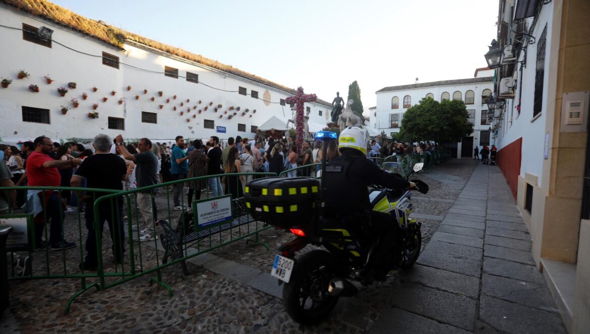 Un policía local pasa en moto por la cruz de mayo de Santa Marina. / Miguel Ángel Salas