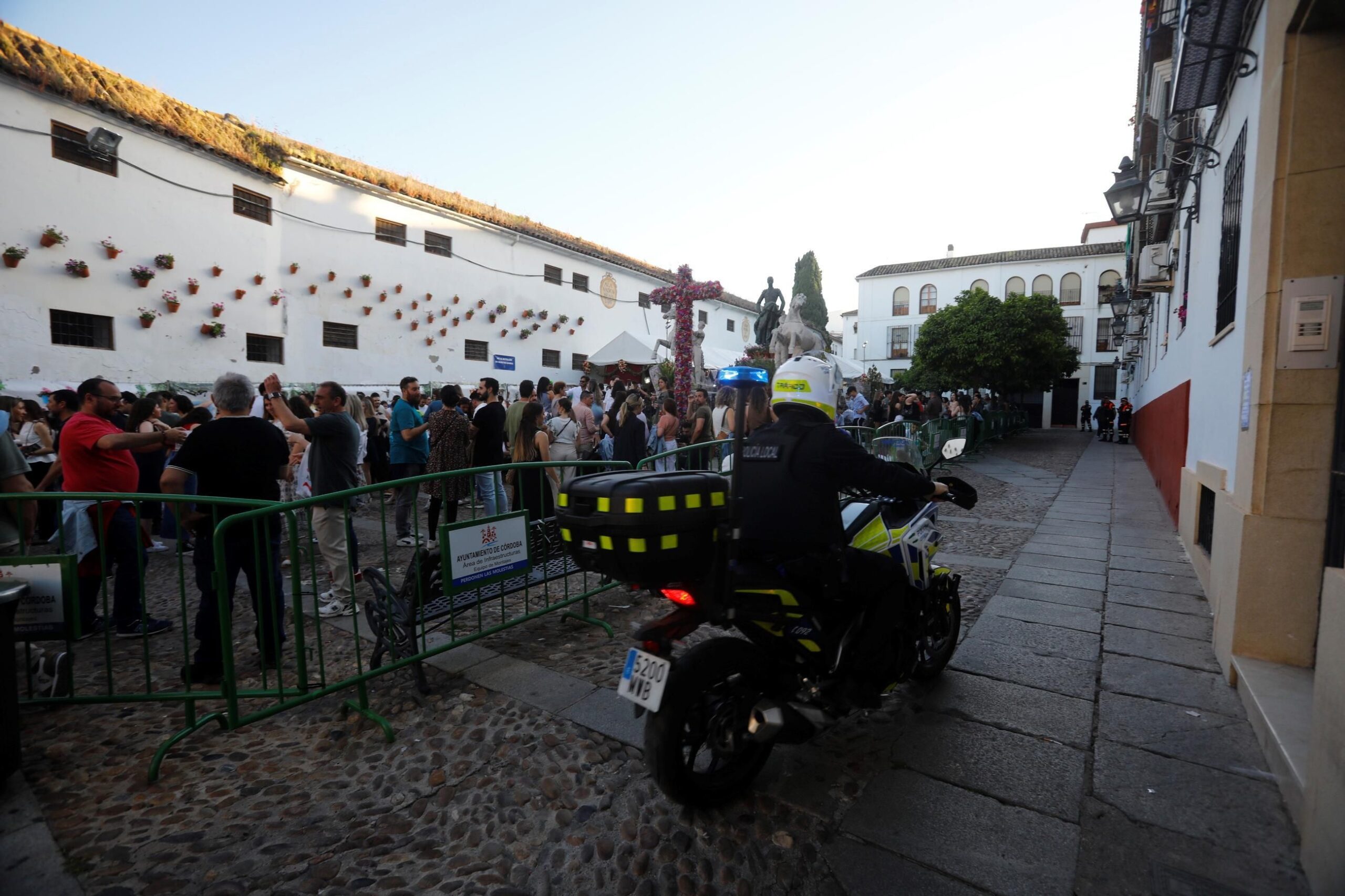 Un policía local pasa en moto por la cruz de mayo de Santa Marina. / Miguel Ángel Salas