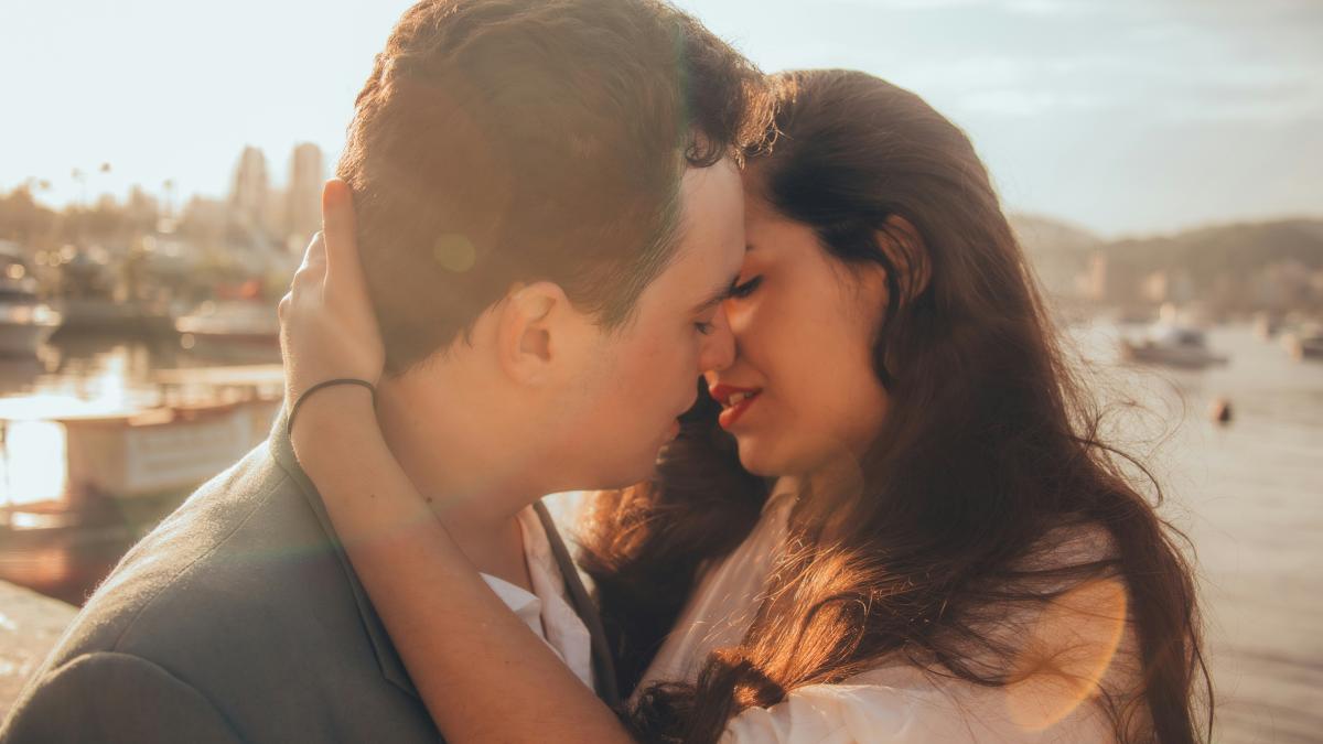 man and woman kissing beside bay