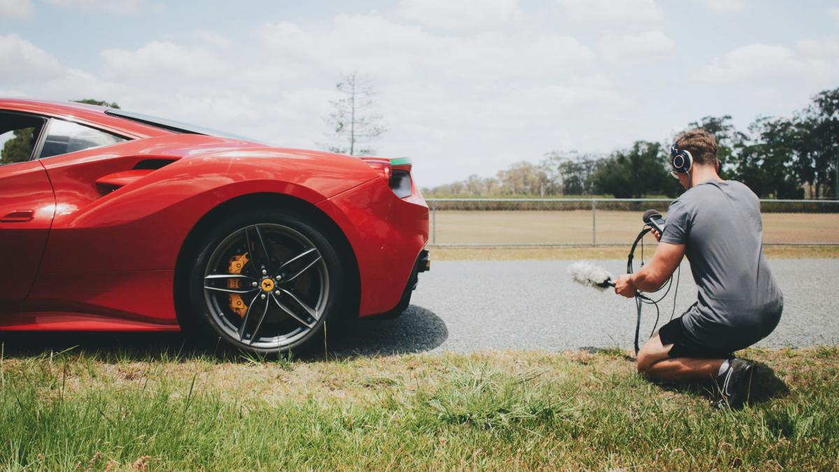 man behind car holding microphone measuring sound