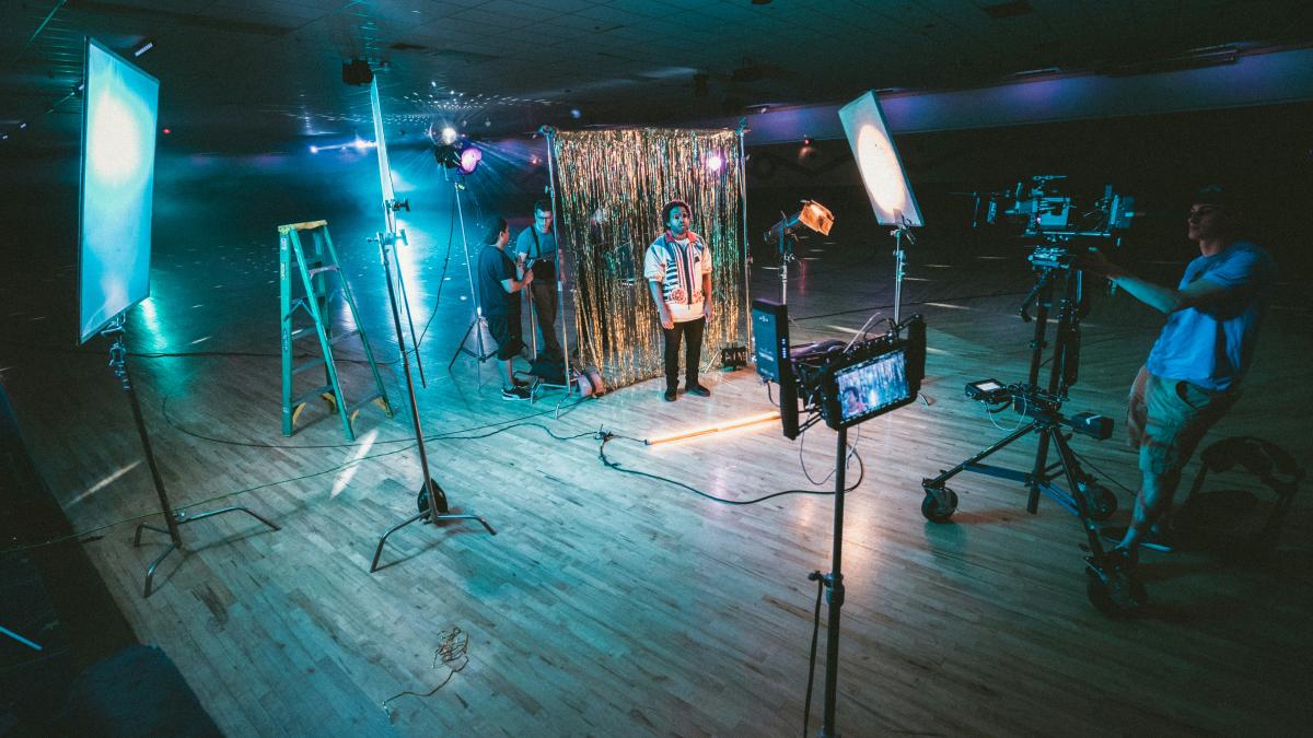 man standing in front of cameras with string lights background