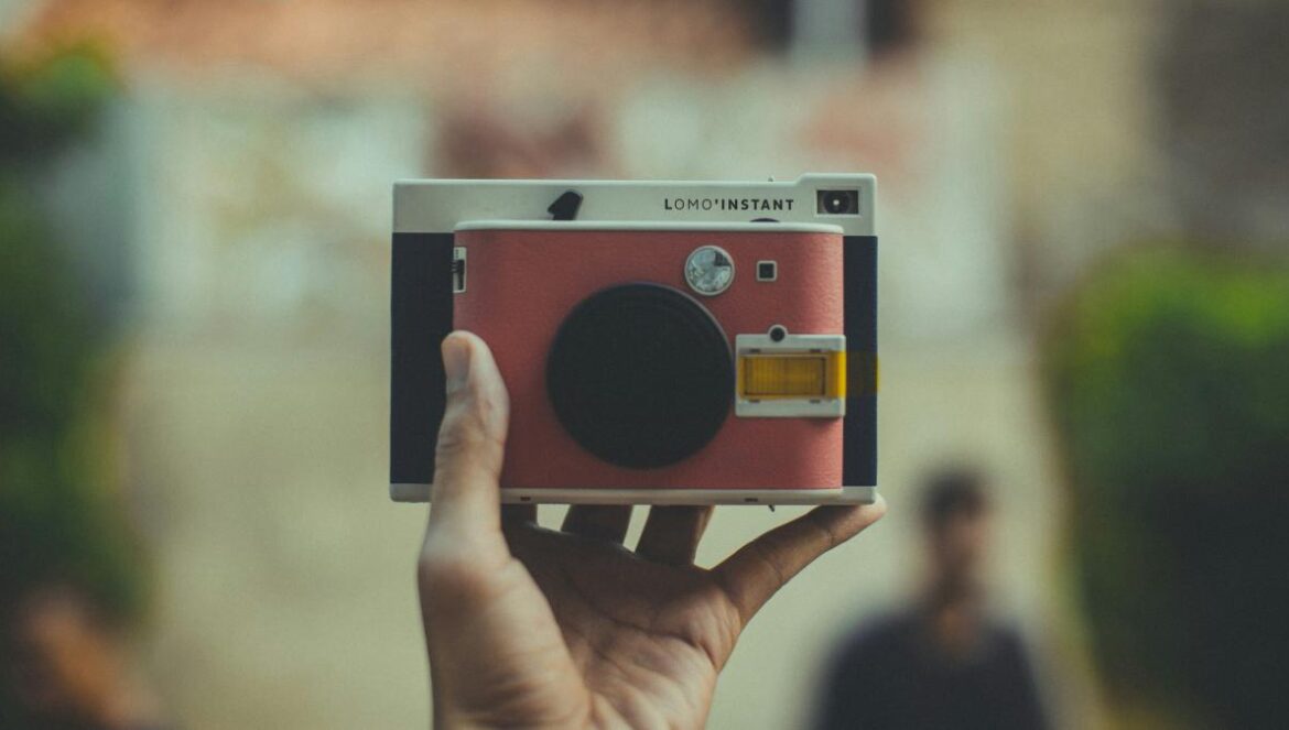 person holding pink and black point-and-shoot camera