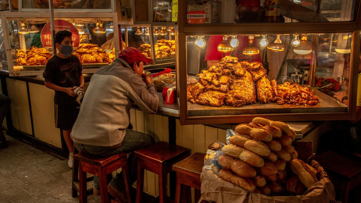 man in gray long sleeve shirt standing in front of food display counter