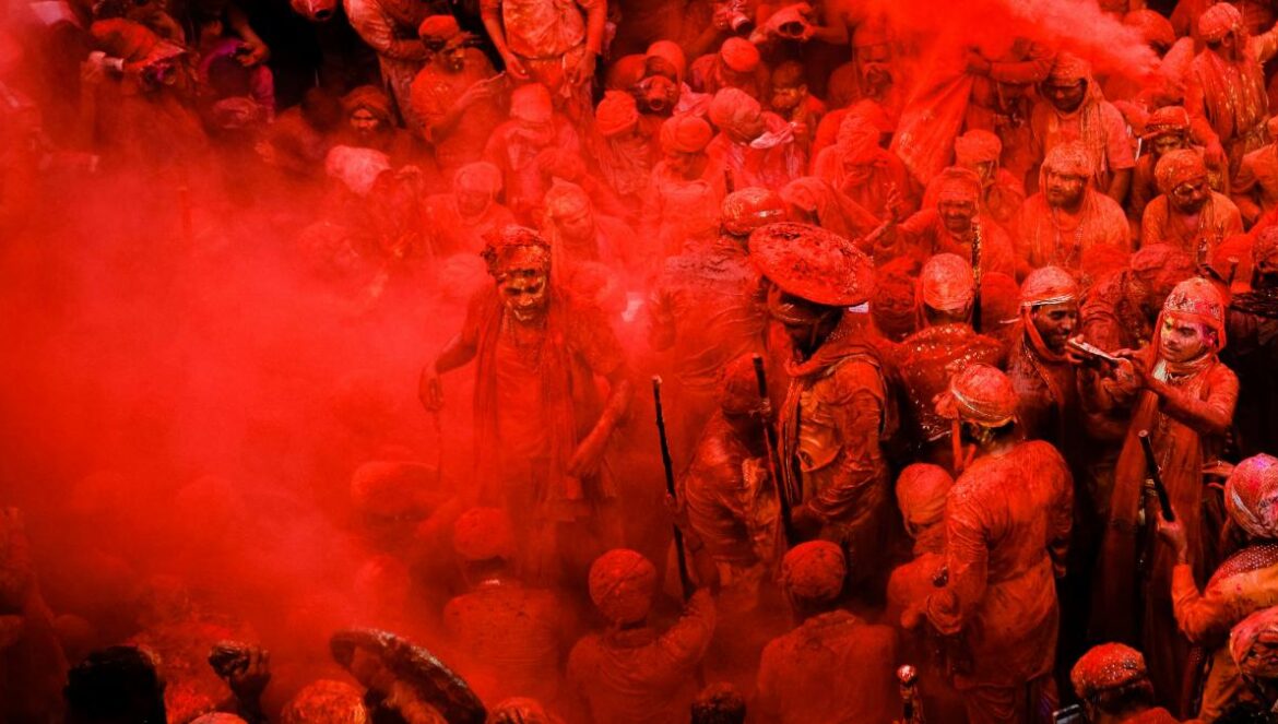 people in blue shirts with red powder on their hands