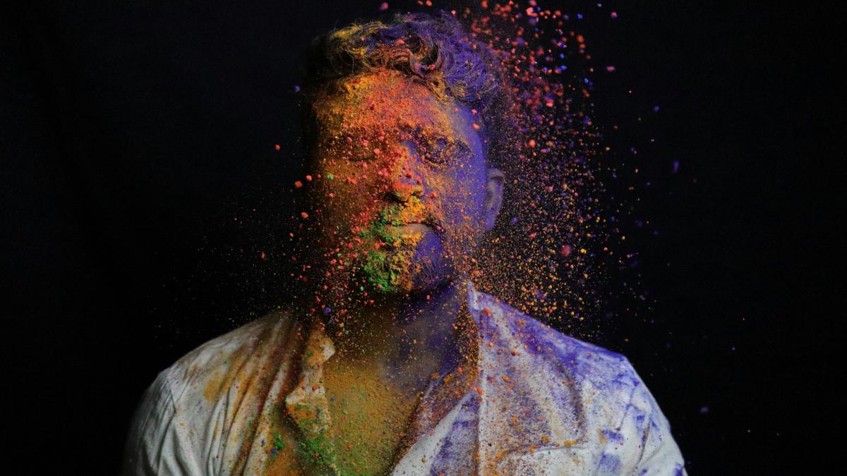 man in white shirt with green and blue powder on his face