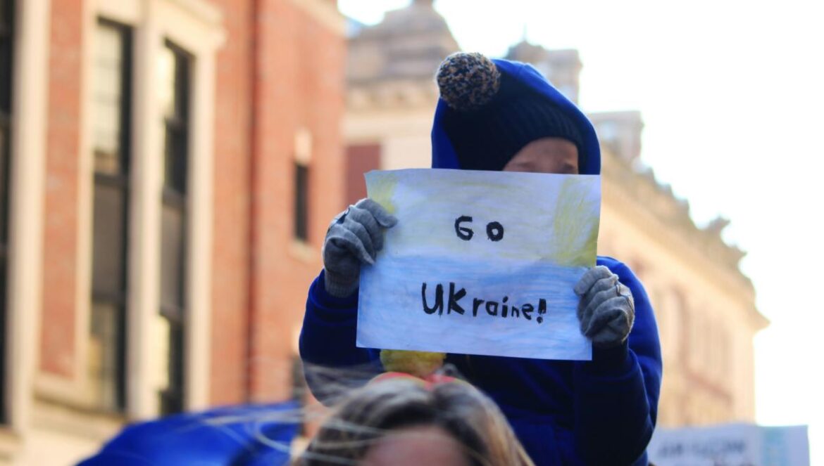 a woman holding a sign that says go ukraine