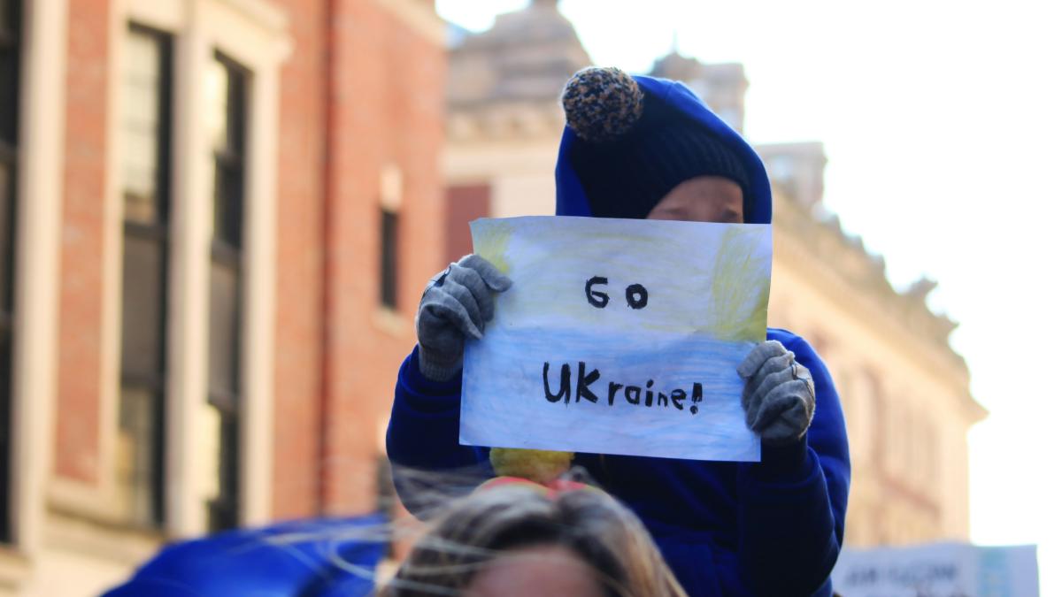 a woman holding a sign that says go ukraine