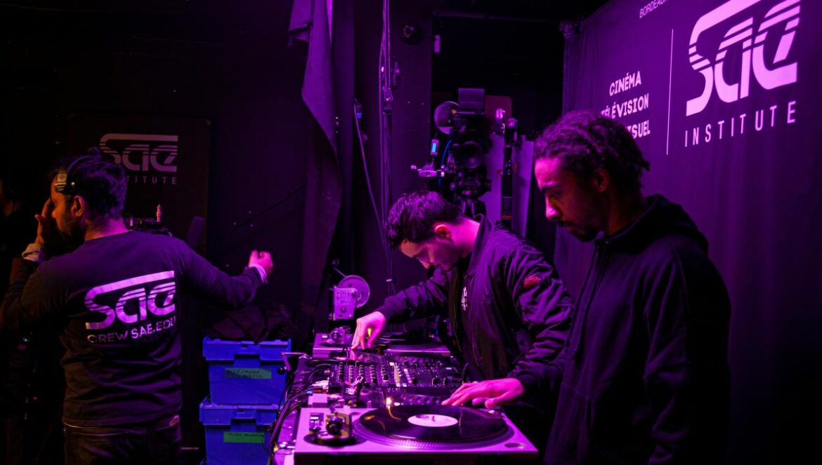 a group of men standing around a dj's turntable