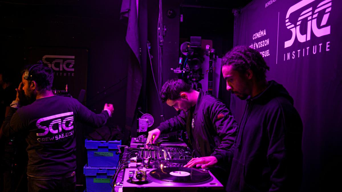 a group of men standing around a dj's turntable