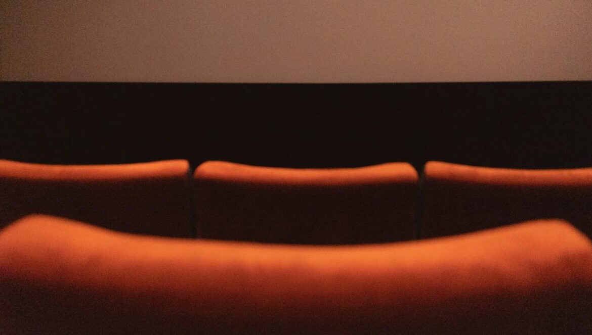 a row of orange couches in front of a projector screen