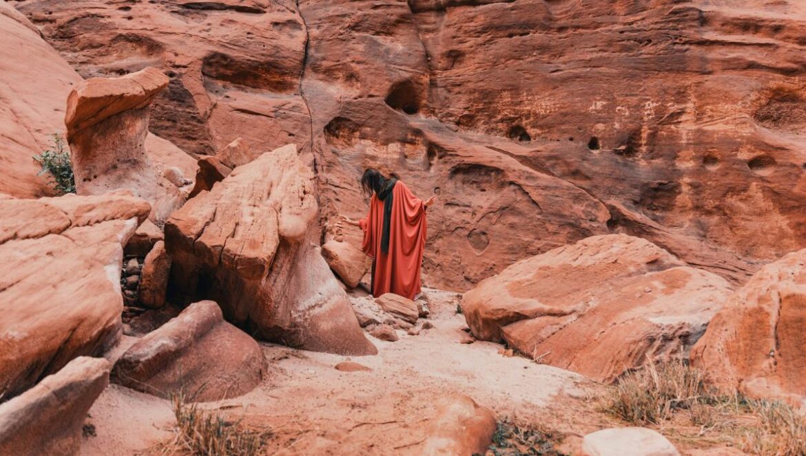 a woman in a red dress standing in a canyon