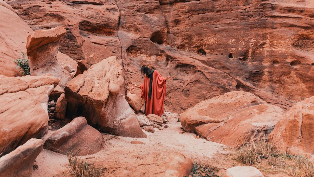 a woman in a red dress standing in a canyon