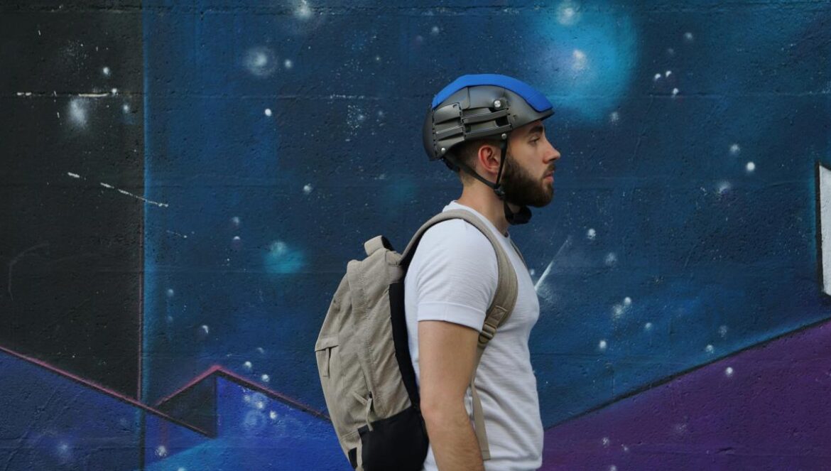 a man with a backpack and helmet walking by a wall