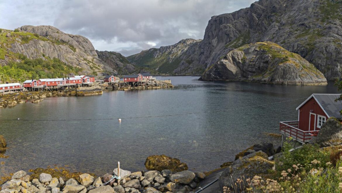 a red house sitting on top of a mountain next to a body of water