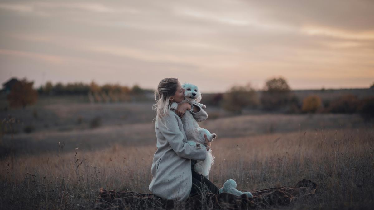 a woman sitting in a field holding a teddy bear