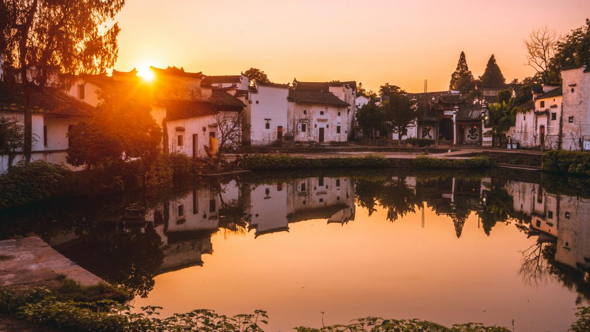 the sun is setting over a small pond