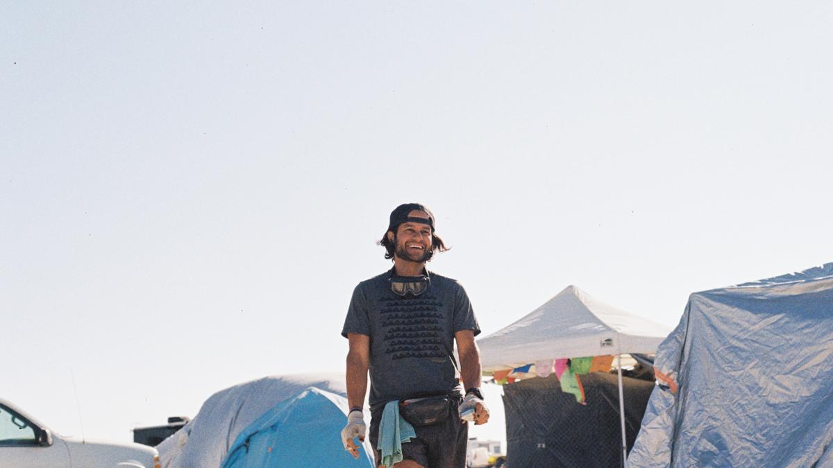 a man standing in front of a tent with a surfboard
