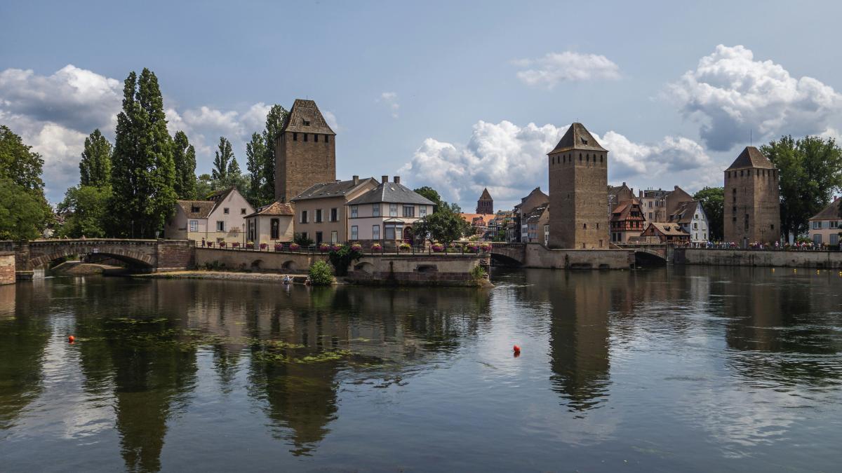 a body of water with buildings and a bridge in the background