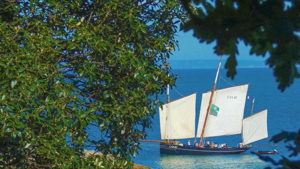 a sailboat sailing on the ocean near a cliff