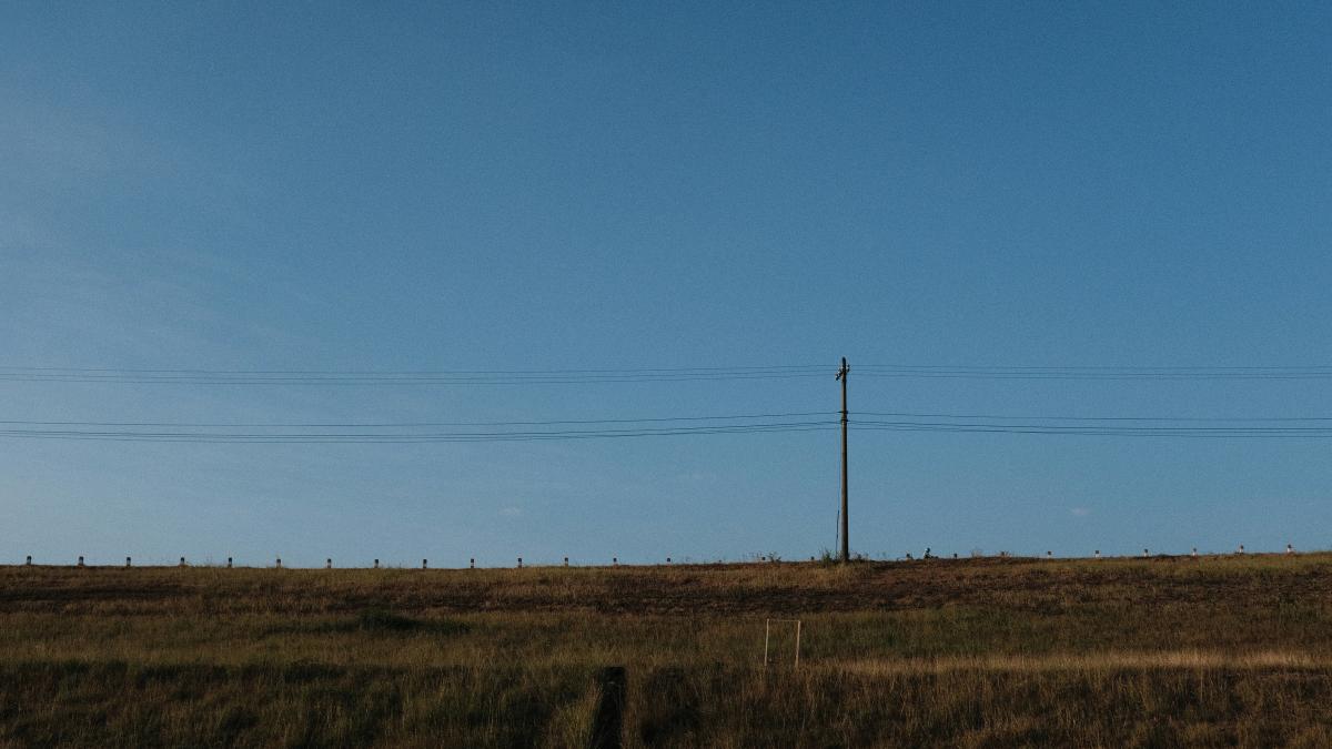 a field with a telephone pole in the distance