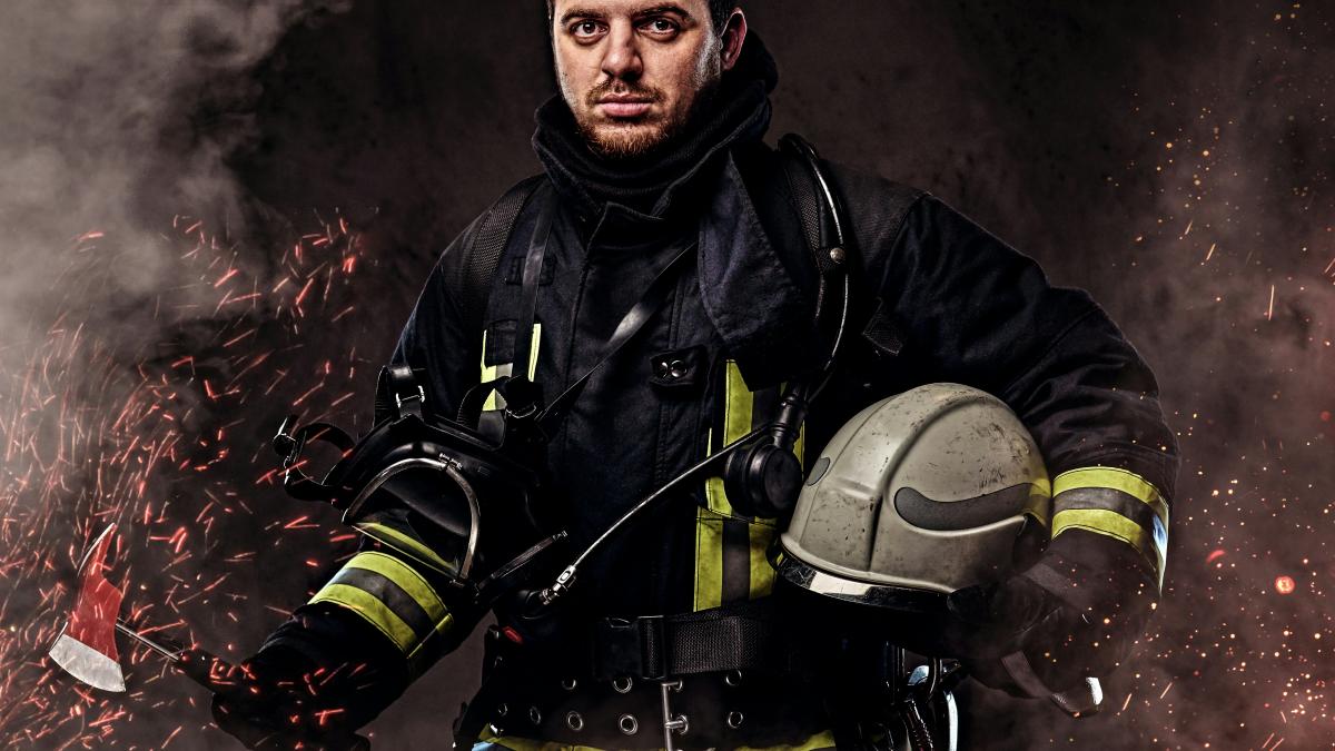 a firefighter holding a helmet and fire hose