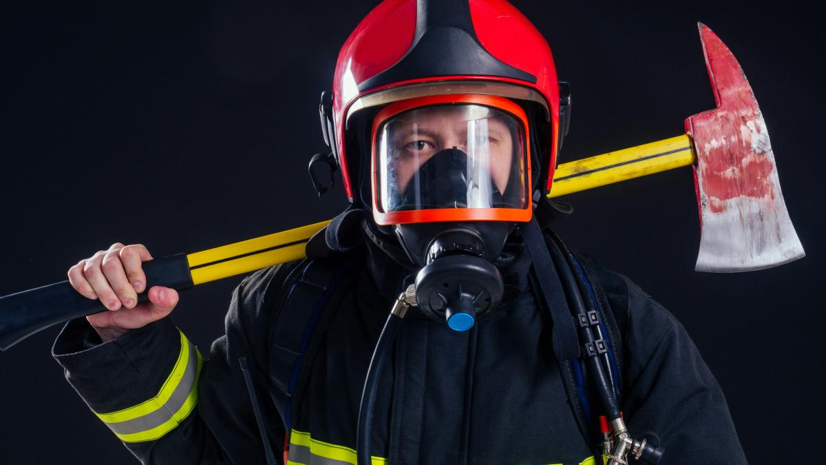 a fireman holding a large axe and wearing a helmet