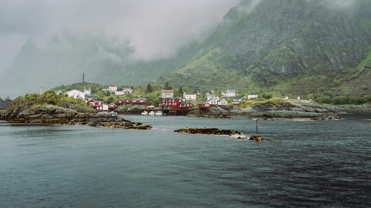 A body of water with houses on a hill in the background