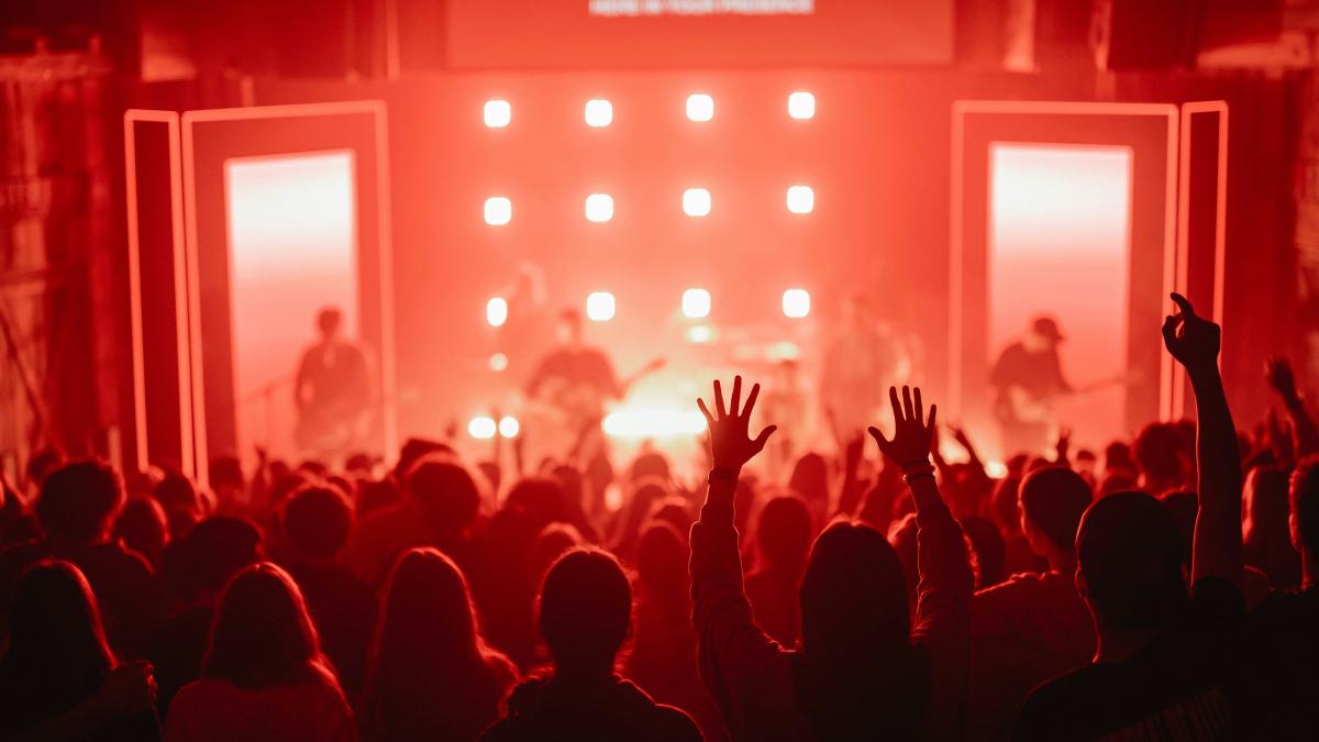 A crowd of people at a concert with their hands in the air