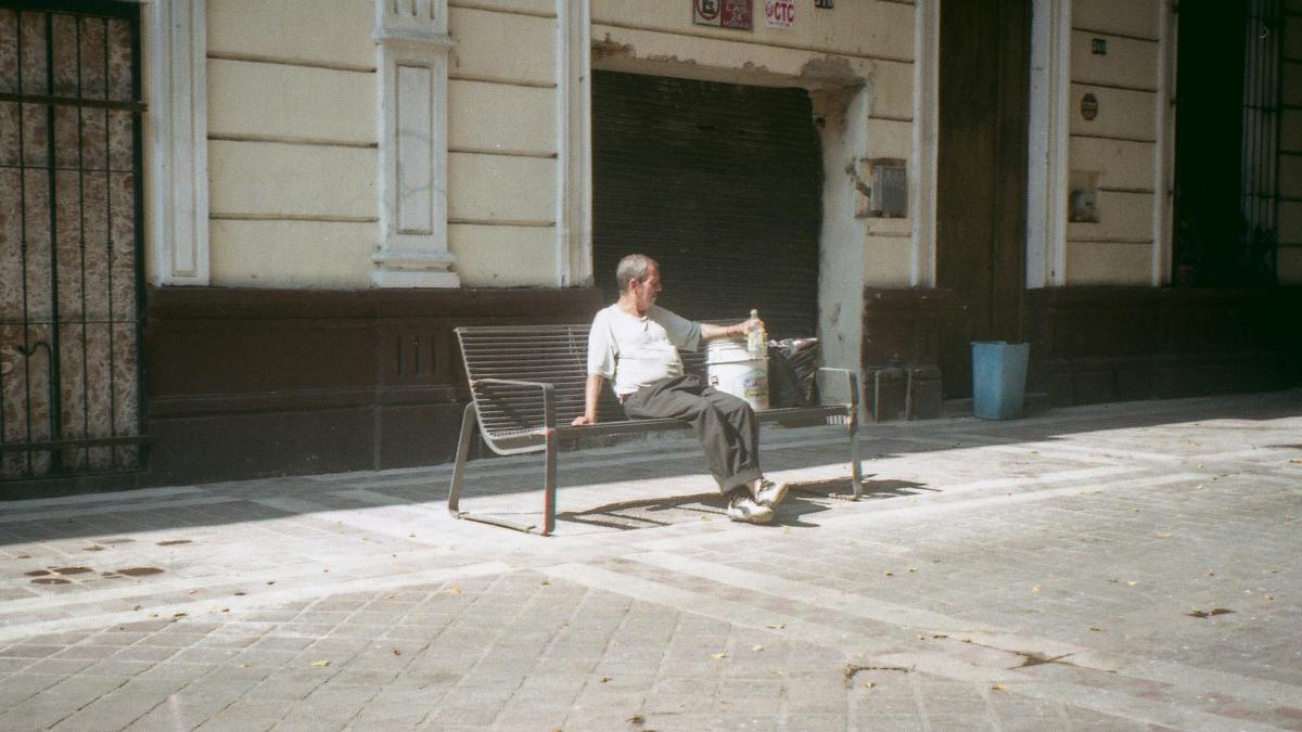 A man sitting on a bench in front of a building