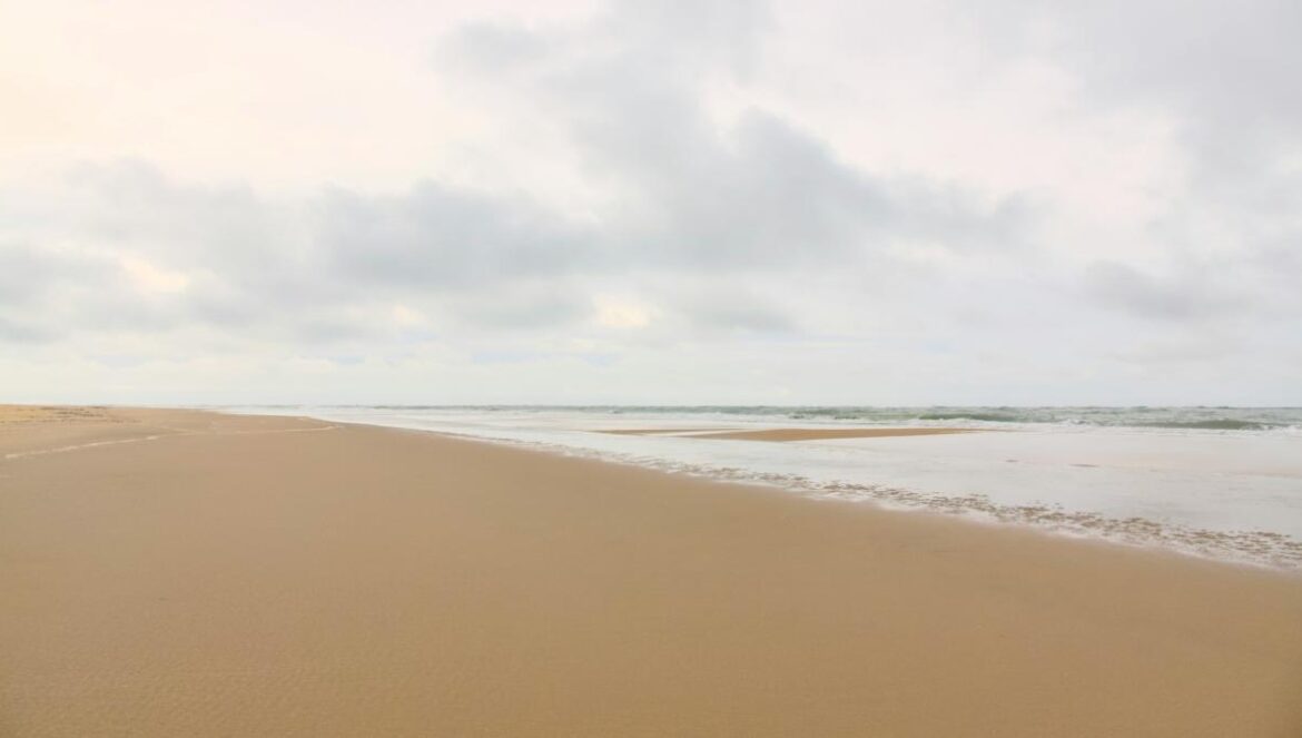 A blurry picture of a beach with a wave coming in