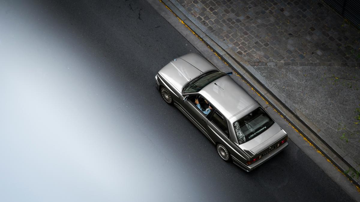 A silver van driving down a street next to a sidewalk