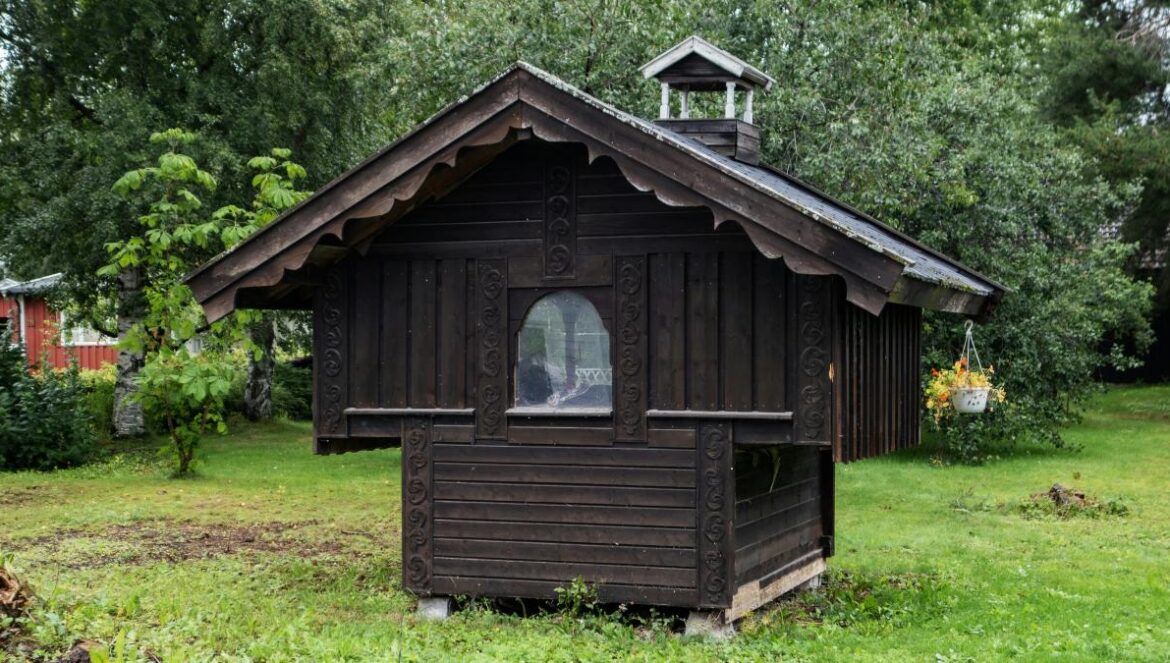 A small wooden building sitting in the middle of a field