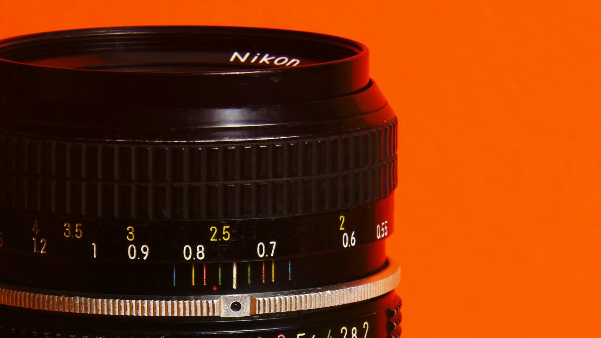 A close up of a camera lens on an orange background