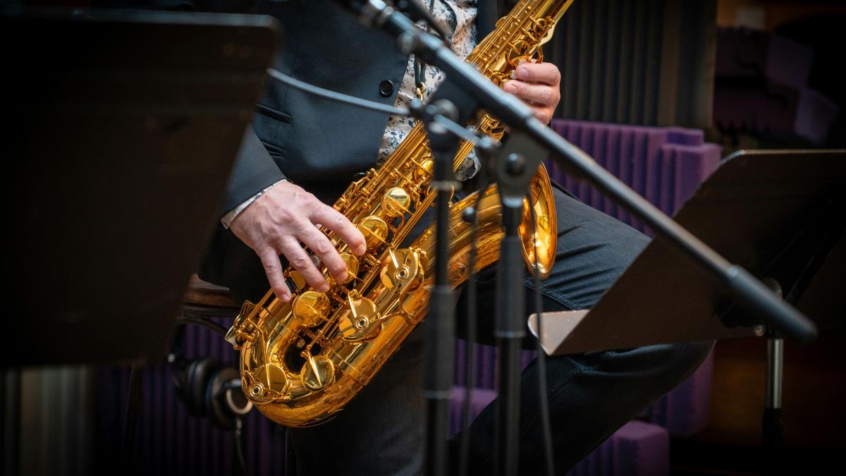 A man playing a saxophone in front of a microphone