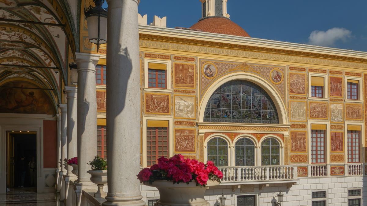 A colorful italian building with columns and flowers.