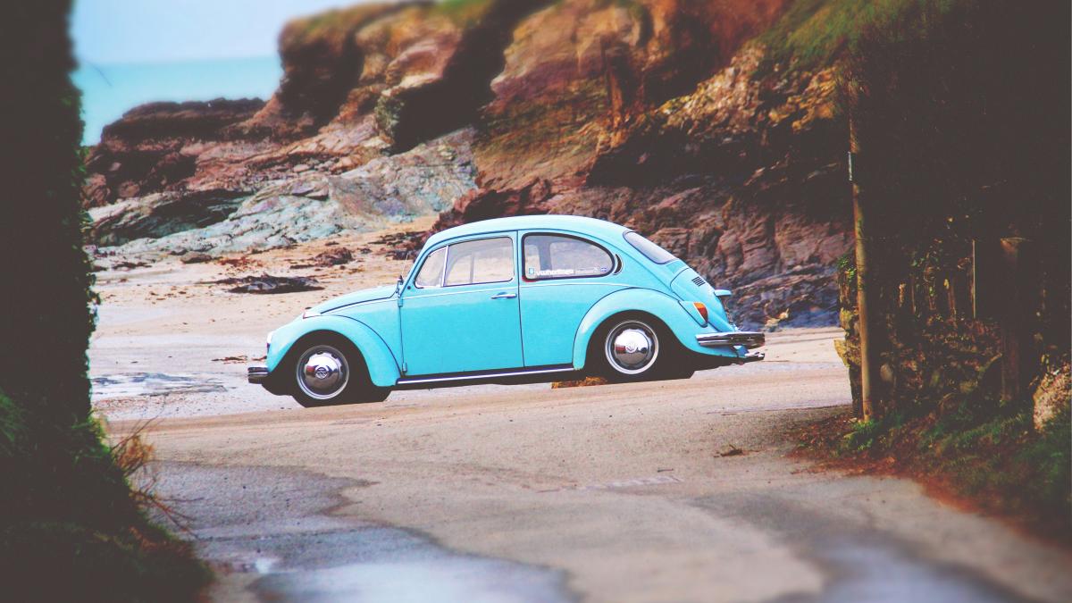 teal Volkswagen Beetle on seashore