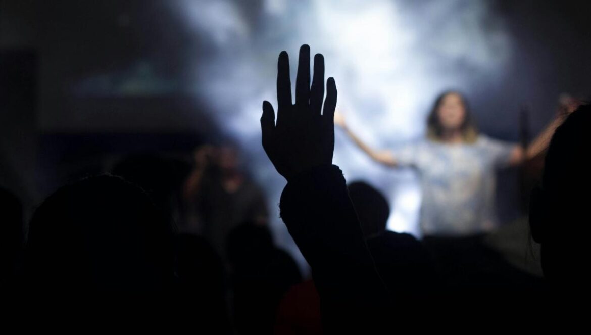 silhouette of person with right hand on air in front of woman on stage