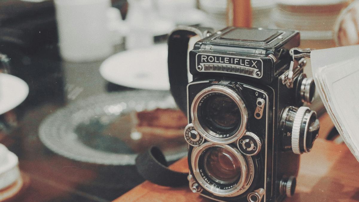 vintage black and gray Rolleiflex camera on wooden desk