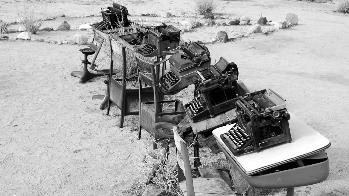 grayscale photo of typewriter on tables