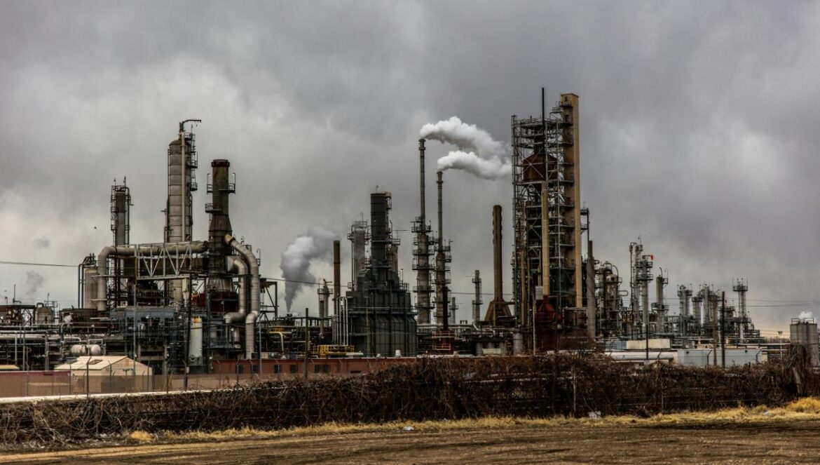 factories with smoke under cloudy sky